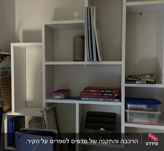 מדף קיר עם ספרים, קופסאות ופריטים שונים